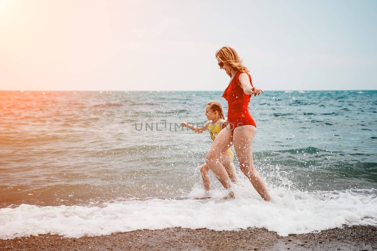 Happy loving family mother and daughter having fun together on the beach. Mum playing with her kid in holiday vacation next to the ocean - Family lifestyle and love concept.