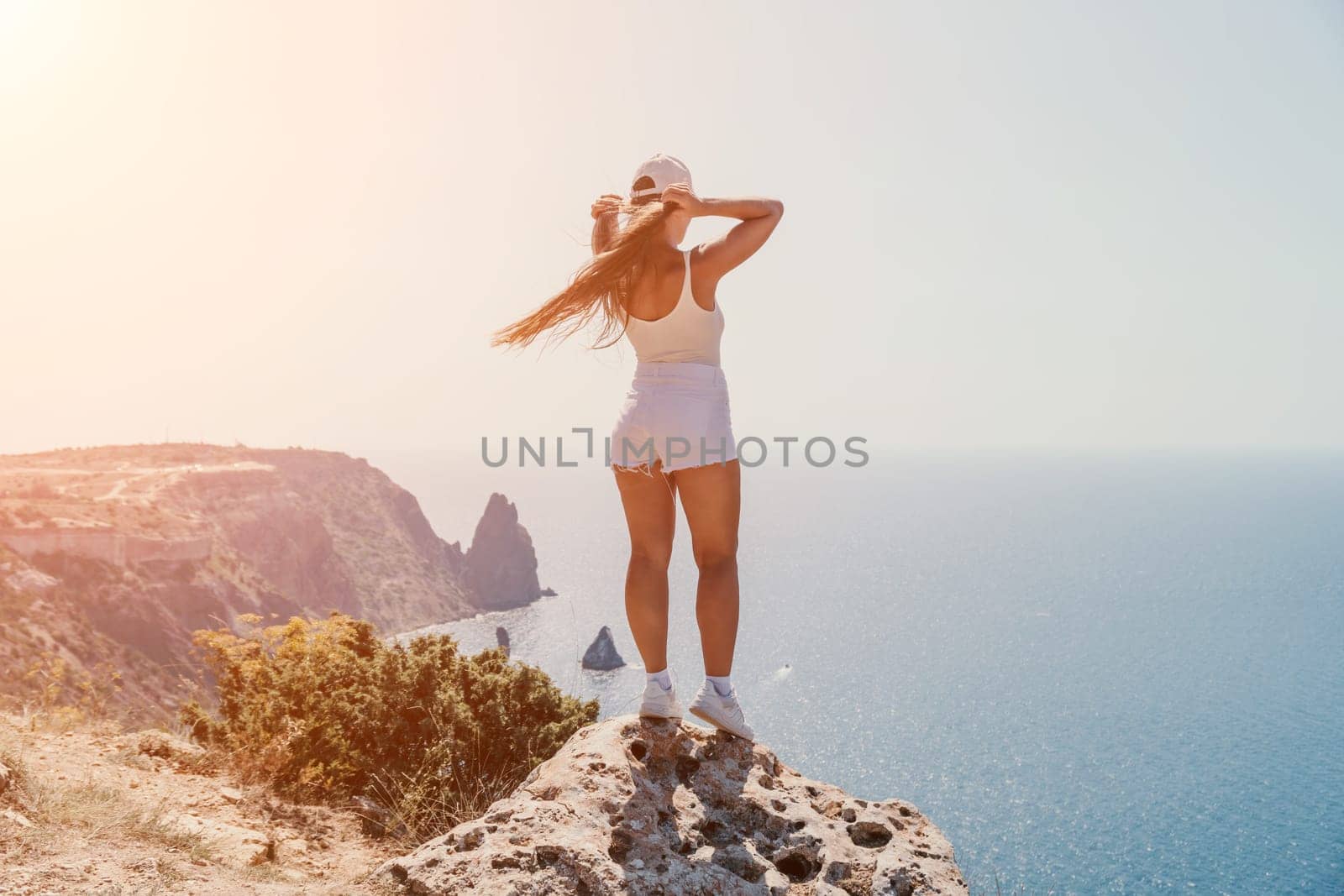 Woman summer travel sea. Happy tourist enjoy taking picture outdoors for memories. Woman traveler posing over sea bay surrounded by volcanic mountains, sharing travel adventure journey by panophotograph