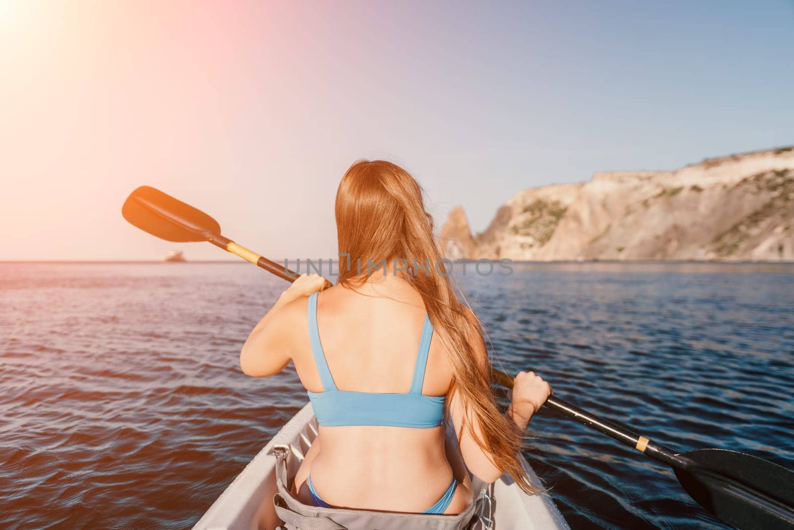 Woman in kayak back view. Happy young woman with long hair floating in kayak on calm sea. Summer holiday vacation and cheerful female people relaxing having fun on the boat. by panophotograph