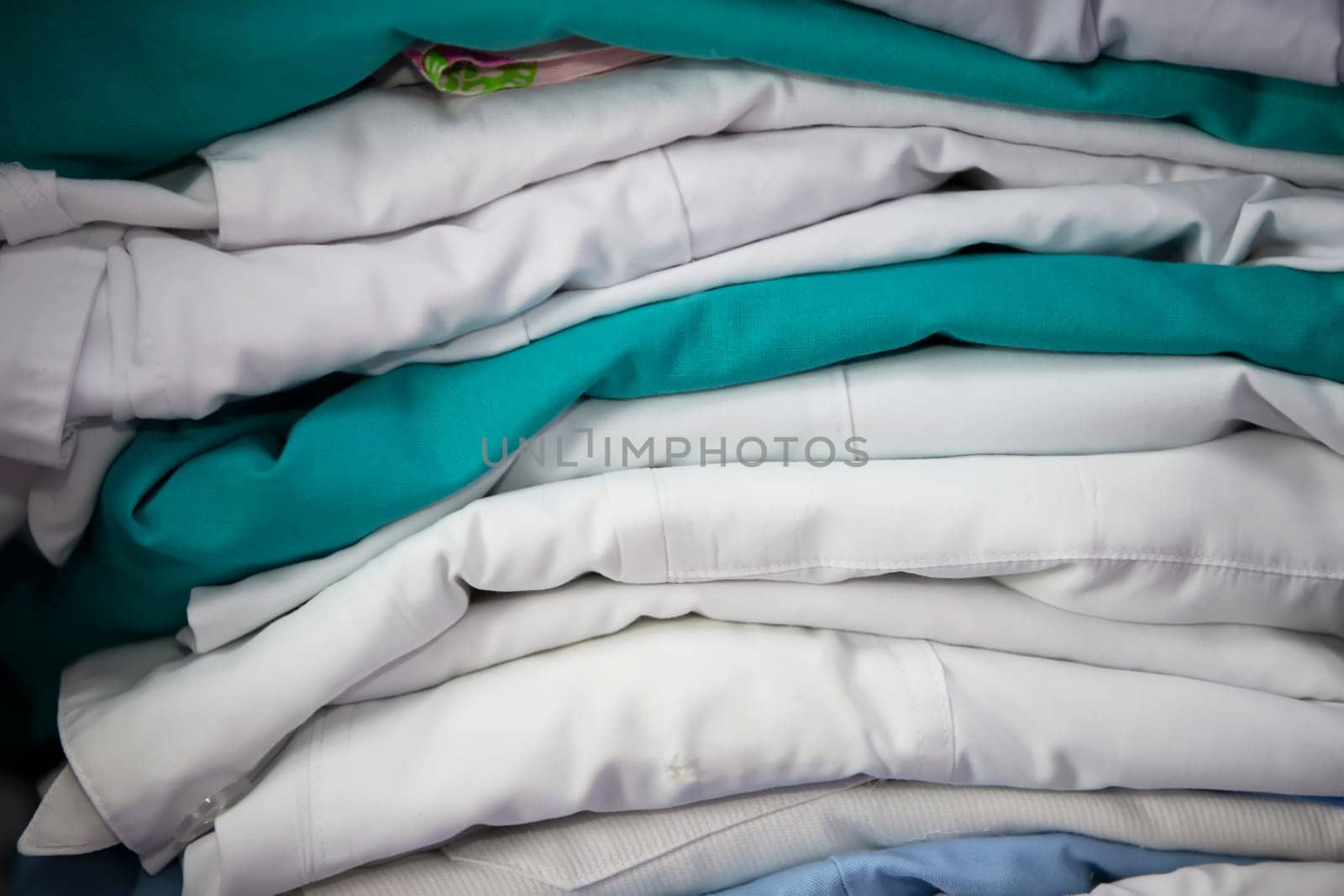 White and green medical gowns are stacked.