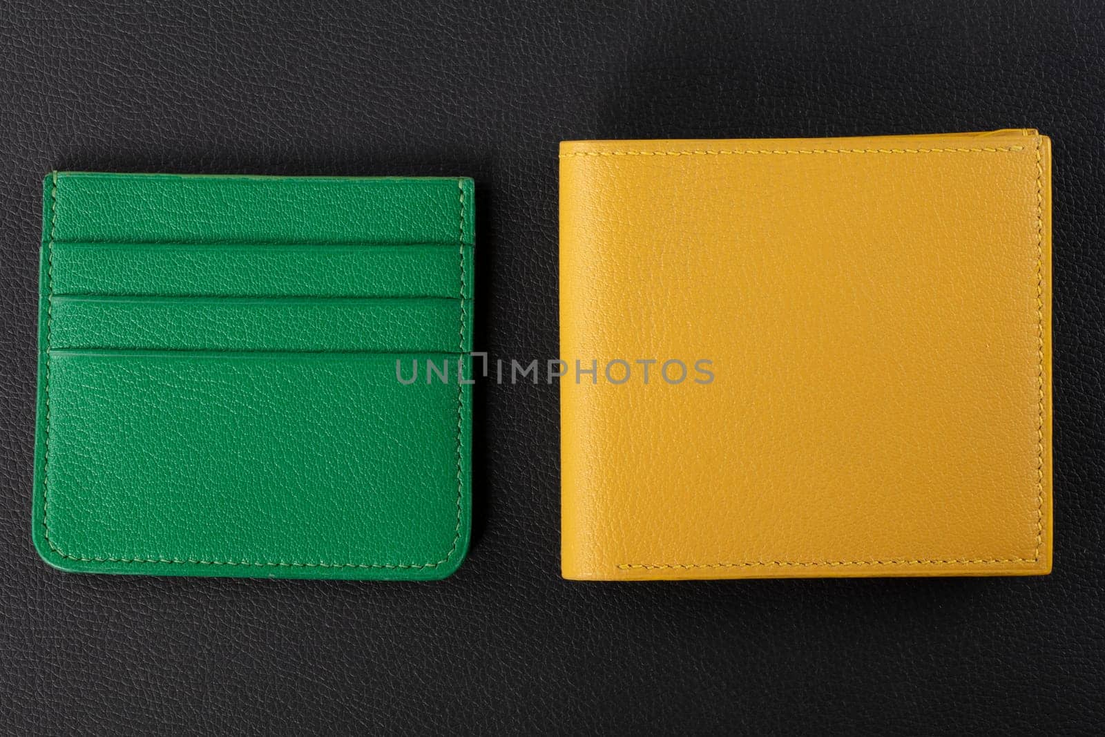 Leather products. Wallet business card holder made of green and yellow genuine leather on a black background.