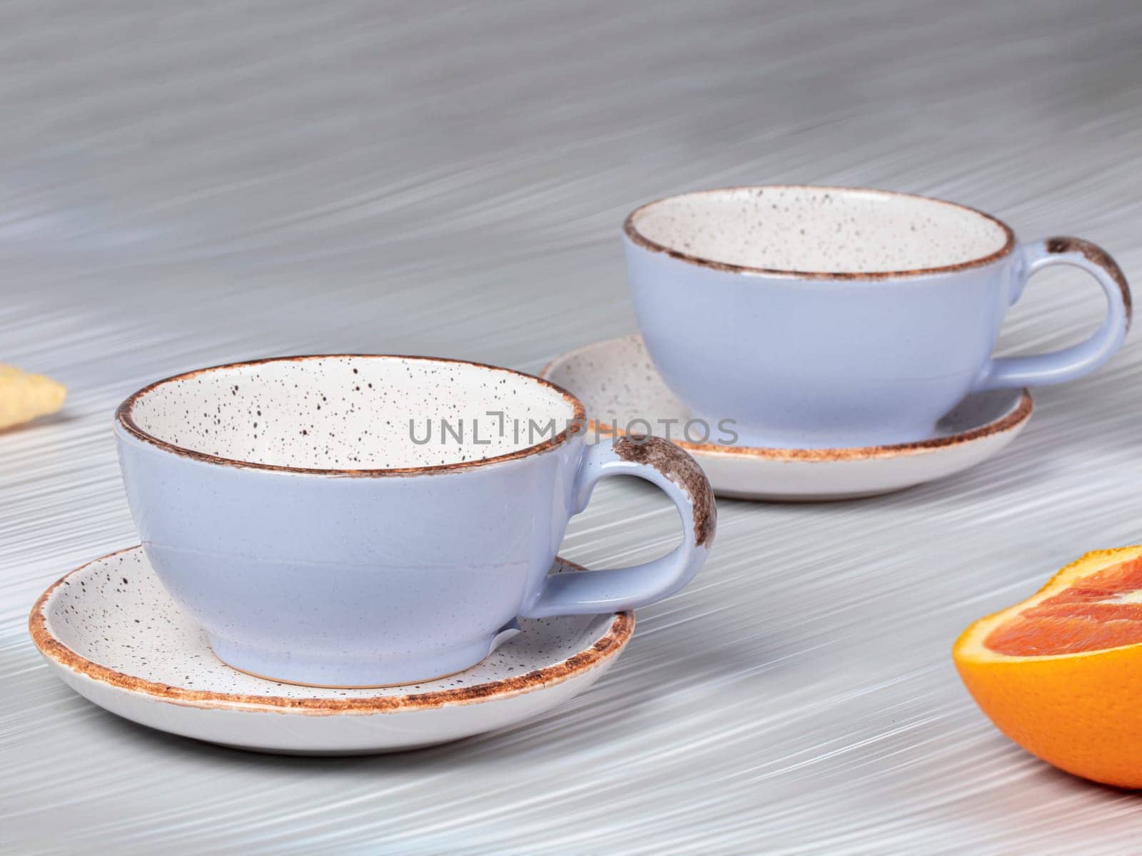 Empty ceramic blue cups with saucers on a gray background. by Sviatlana