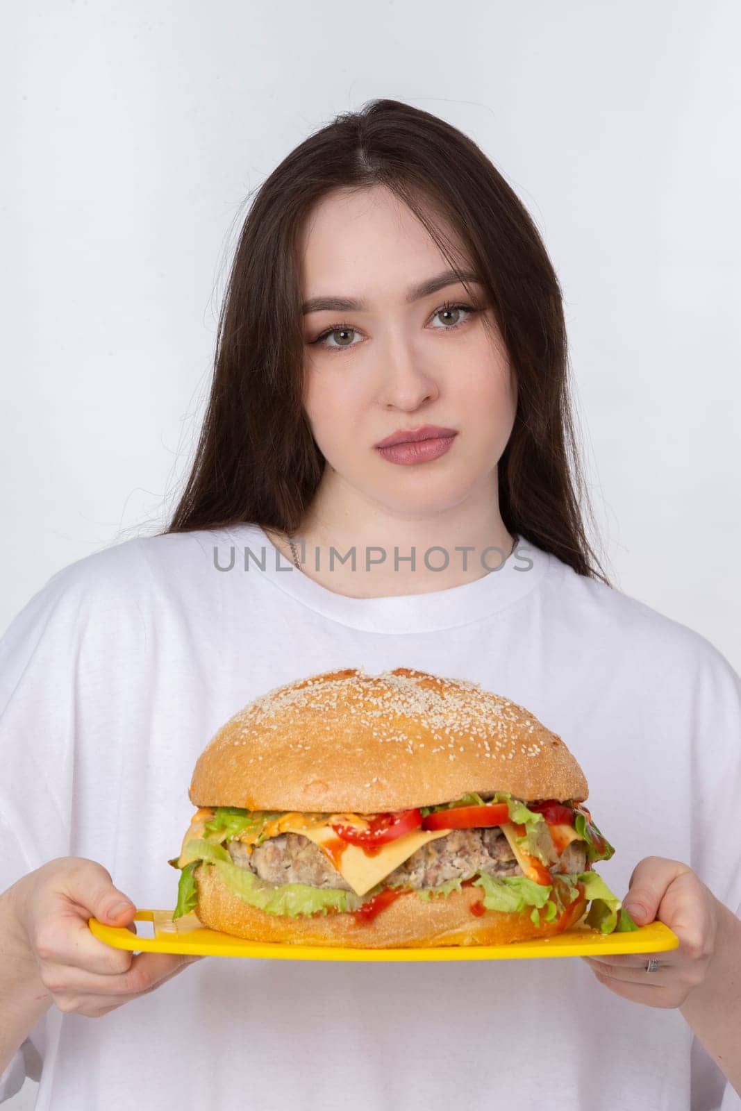 A woman is holding a big barbecue hamburger sandwich on the background. Fast food concept. The girl has a huge hamburger. by Sviatlana