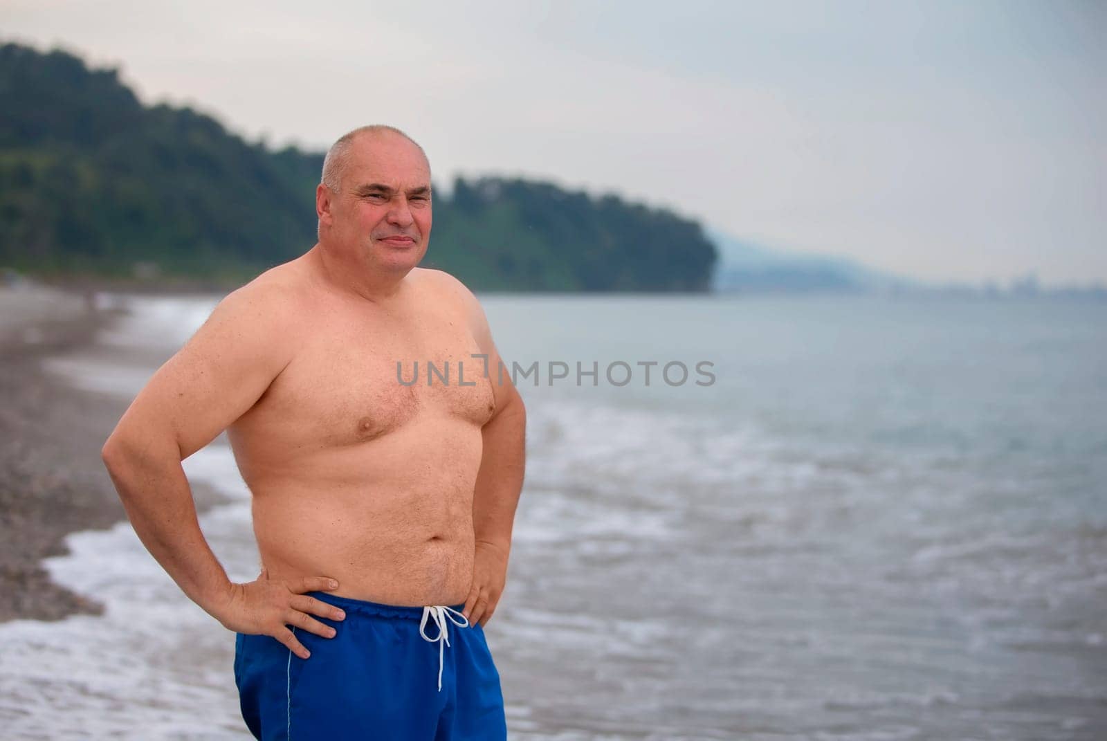 An elderly man of athletic build on the background of the sea. by Sviatlana