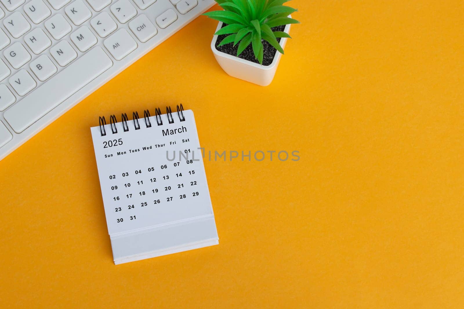 March 2025 desk calendar on yellow background. Directly above. Flat lay. Copy space.