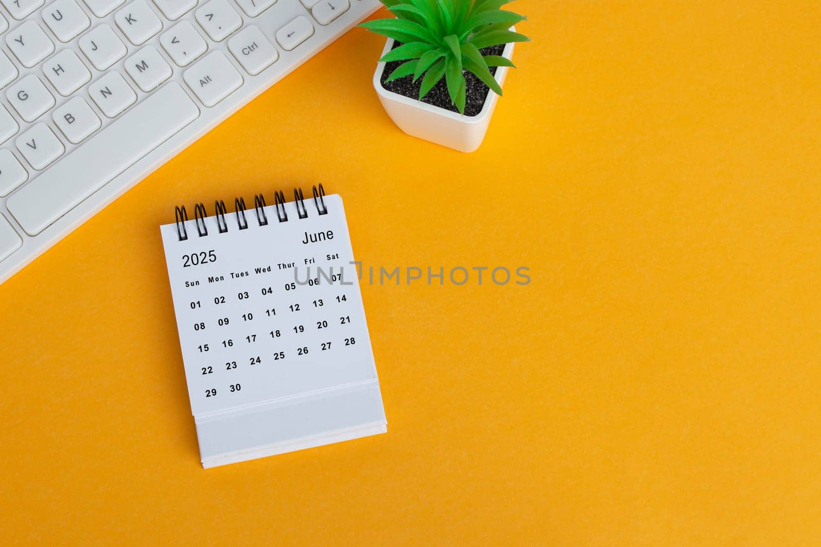 June 2025 desk calendar on yellow background. Directly above. Flat lay. Copy space.