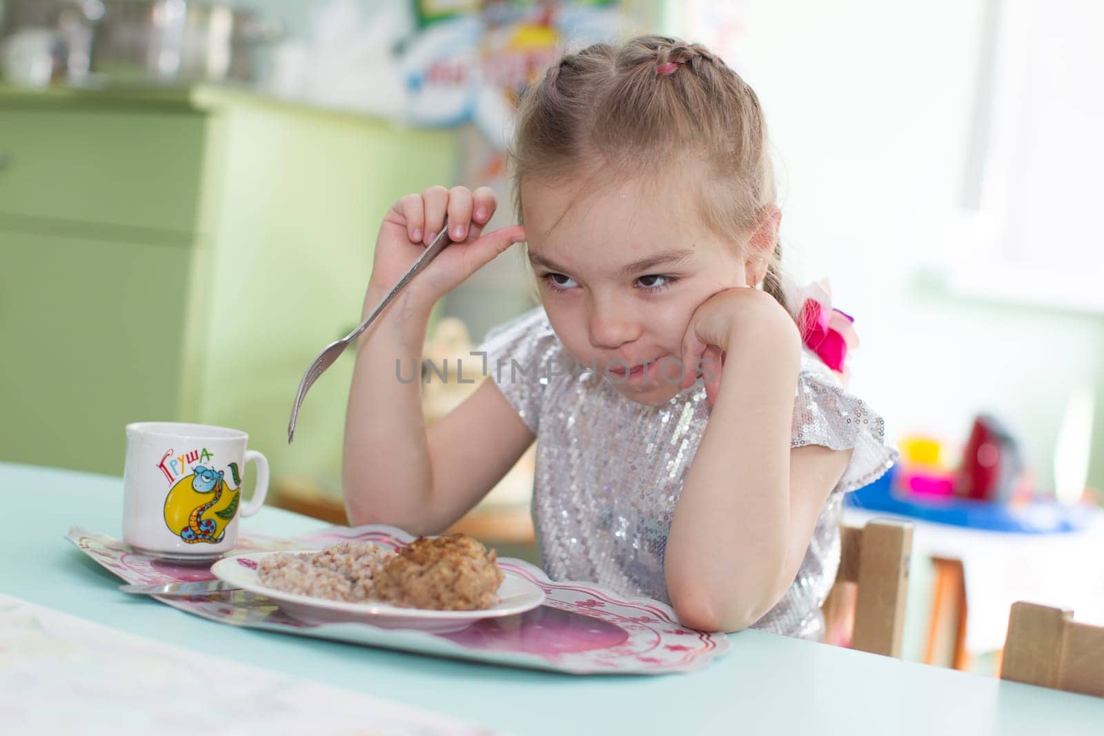 Belarus, Gomel, May 29, 2018. The kindergarten is central. Open Day.Сhild does not want to eat. Bad appetite. Eating in kindergarten by Sviatlana