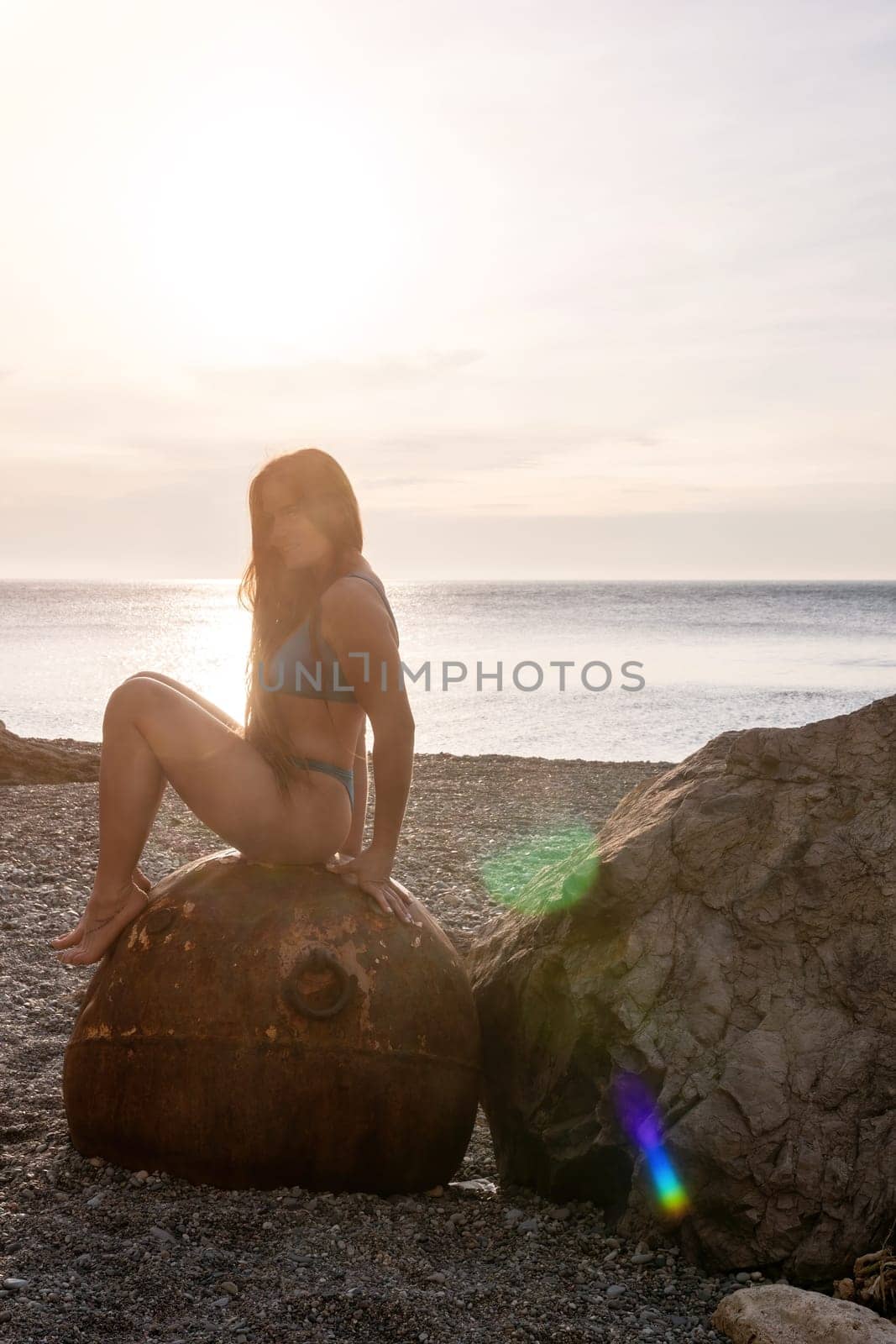 Woman summer travel sea. A happy tourist enjoys taking pictures of her travels, posing by an old, rusty sea mine on a beach surrounded by volcanic mountains, sharing travel adventure journey by panophotograph