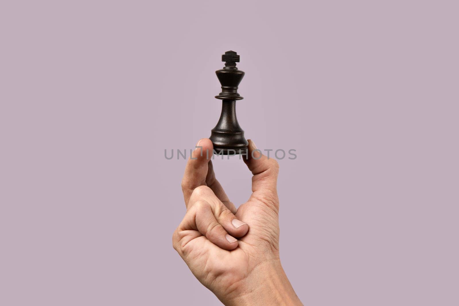 Male hand holding king chess figure on purple background. by TropicalNinjaStudio