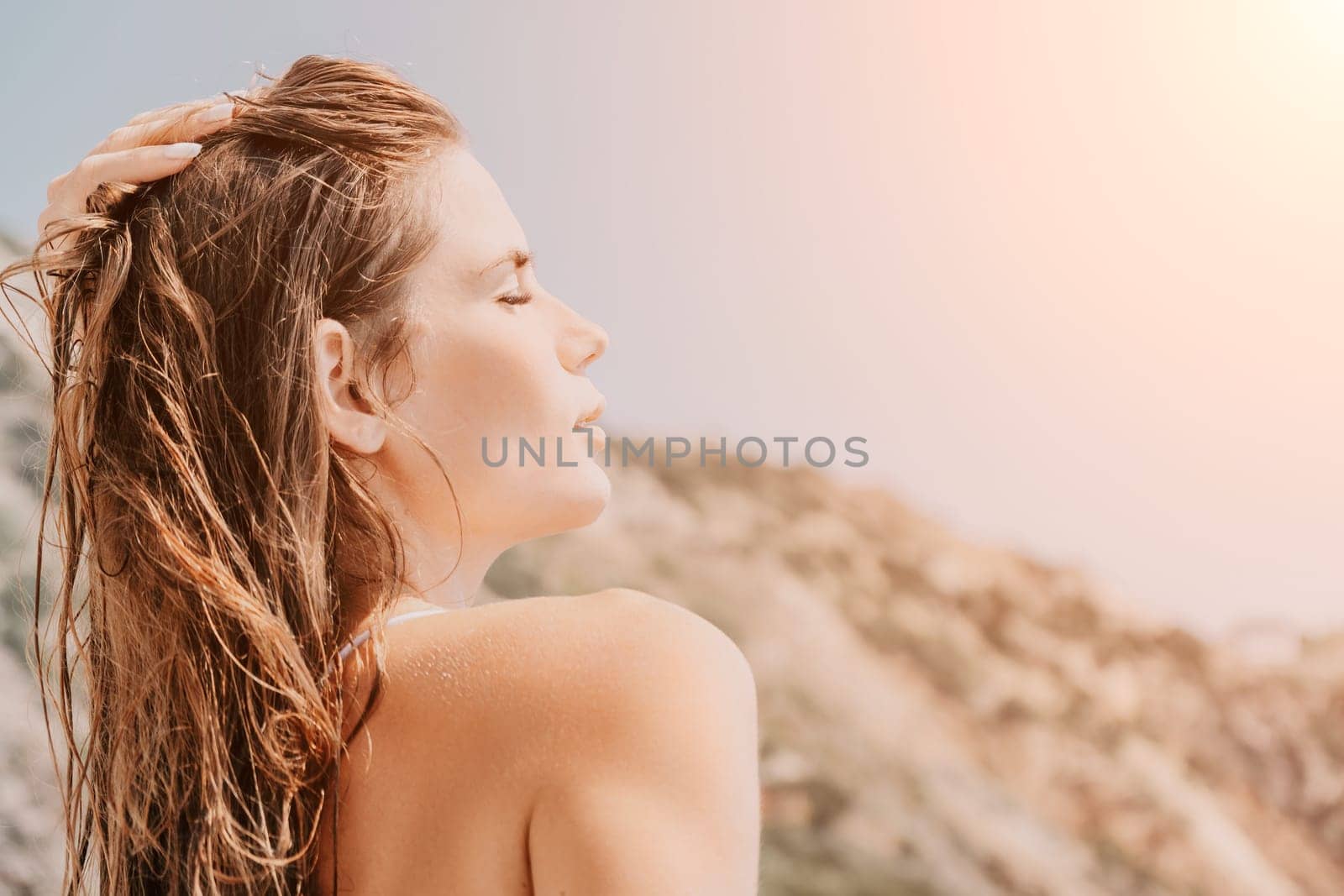 Woman travel sea. Happy tourist in white bikini enjoy taking picture outdoors for memories. Woman traveler posing on the beach at sea surrounded by volcanic mountains, sharing travel adventure journey by panophotograph