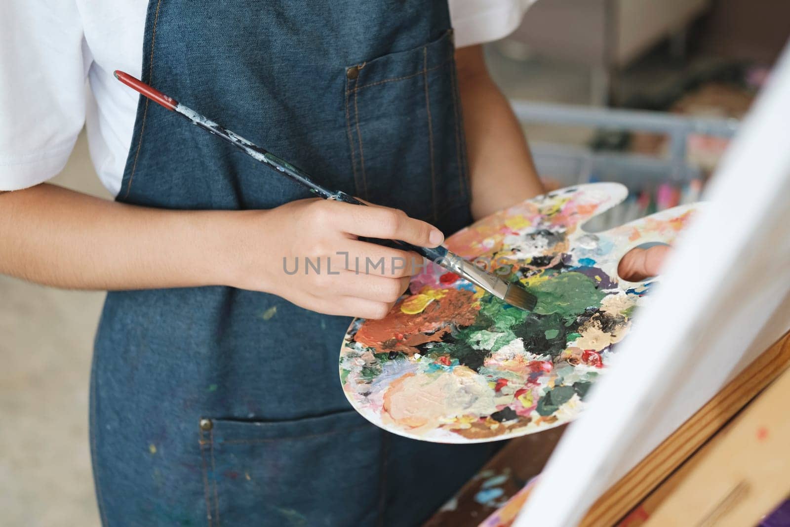 Young Asian female artist painting on canvas doing art projects on her studio. by ijeab