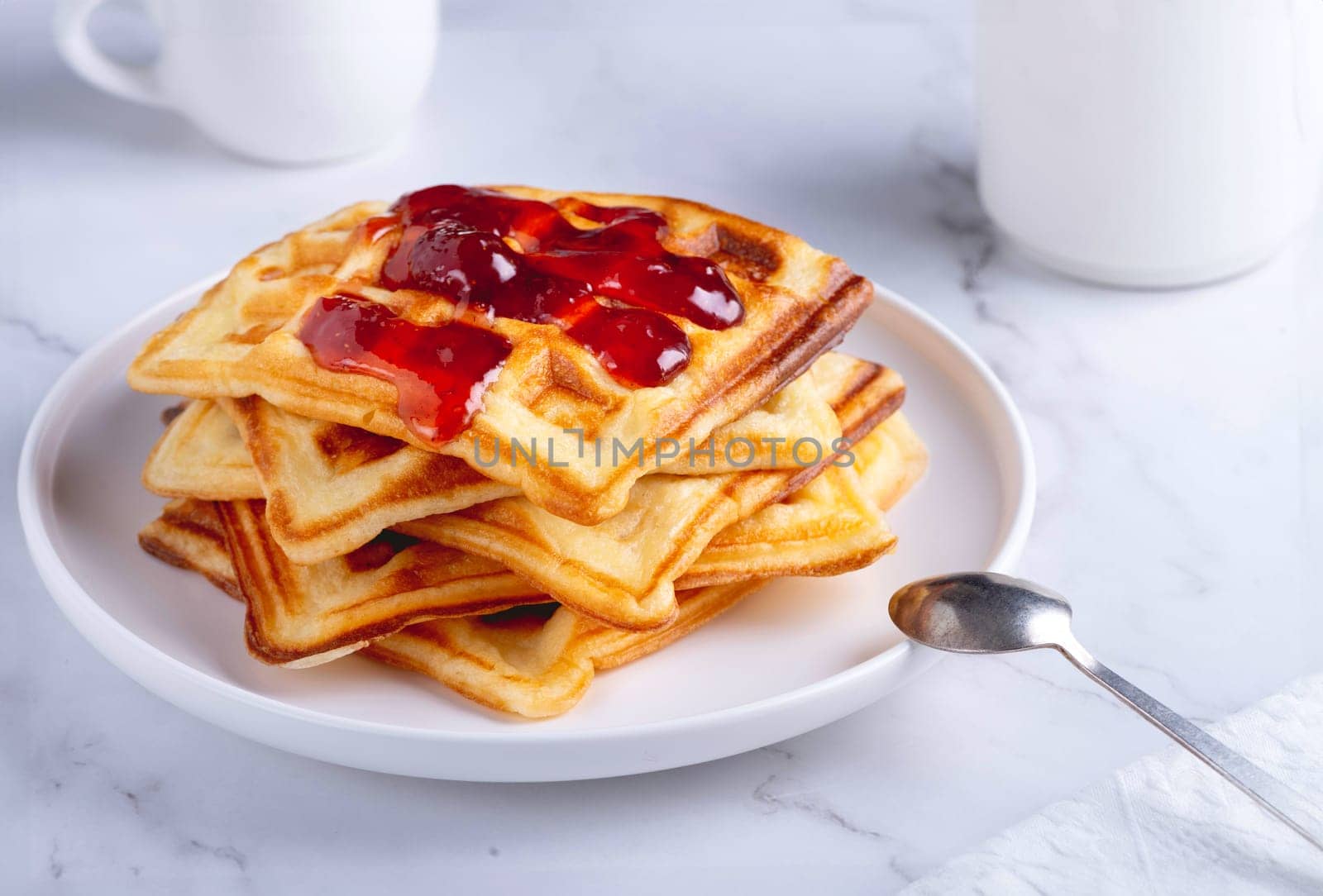 Belgian waffles with strawberry jam on a white background.