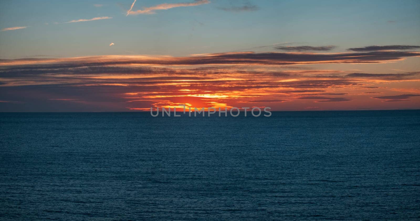 Stunning ocean sunset with vivid sky hues & tranquil sea.