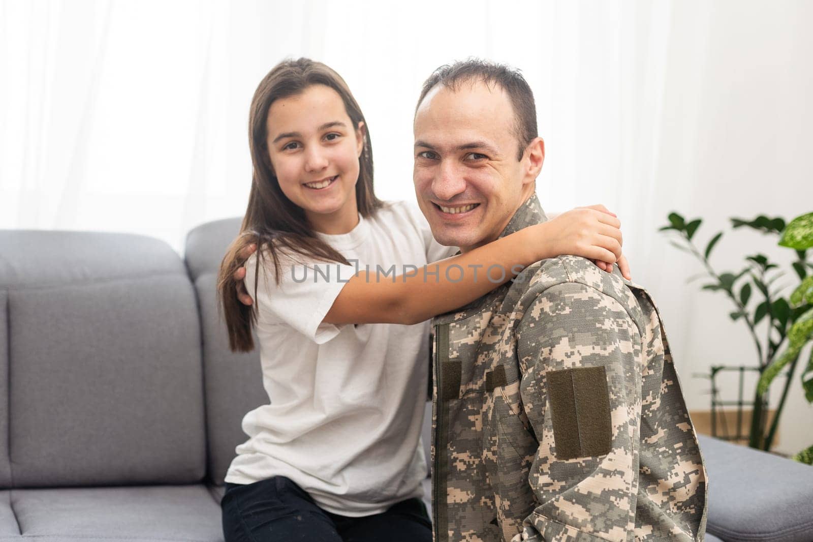 Little girl hugging her military father at home, closeup by Andelov13