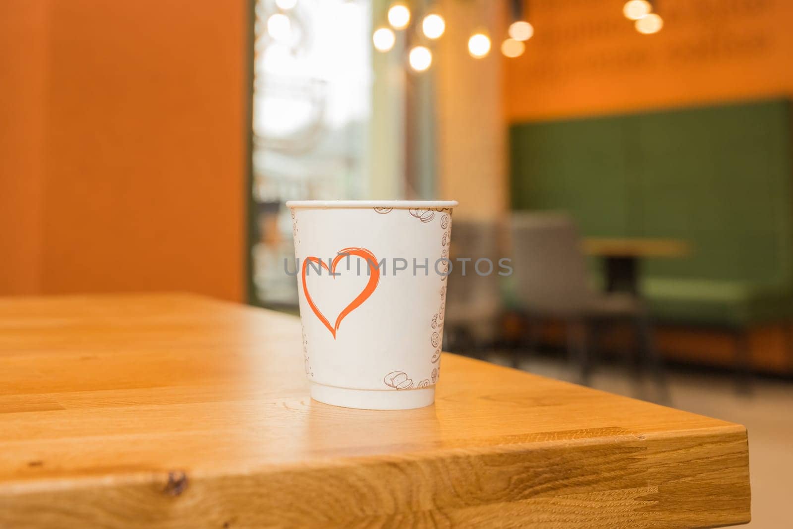 Takeaway coffee. Paper cup of coffee on wooden table in cafe blur background. Hot coffee . Copy space for text. Selective focus. The atmosphere is warm coffee shop. Drinking concept.