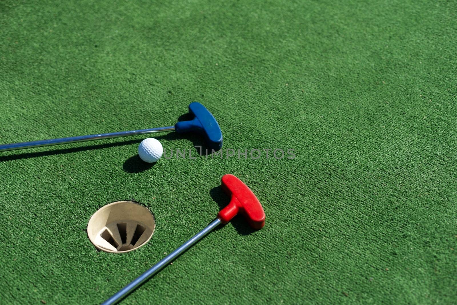colorful golf putters with golf balls on synthetic grass.