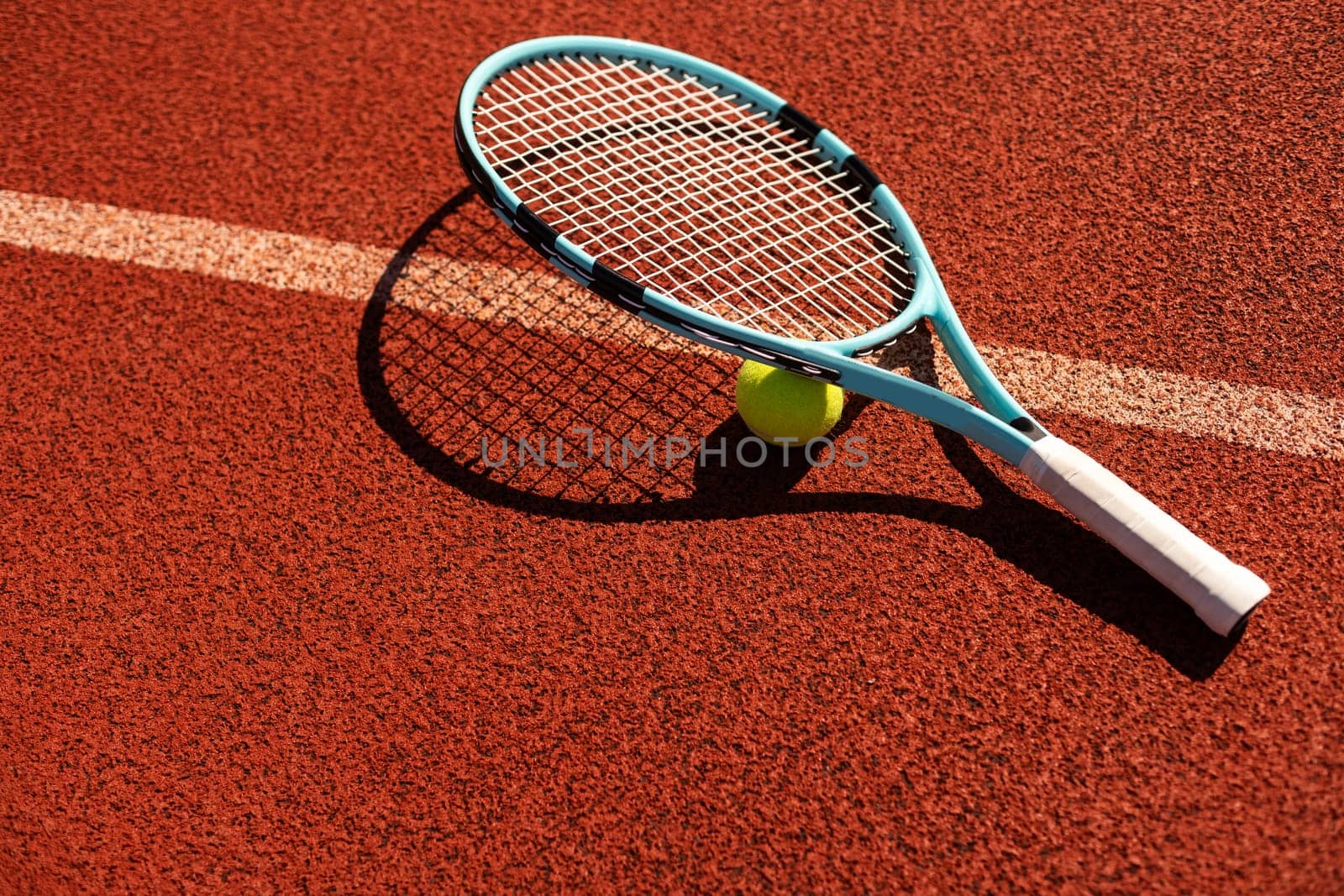 Balls and racket are lying on clay brown professional tennis court Close up of tennis balls and racket on dross at tennis court on the playground. Sport concept. Perspective up top view . High quality photo