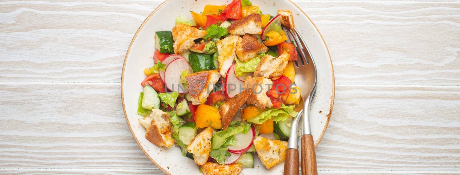 Traditional Levant dish Fattoush salad, Arab cuisine, with pita bread croutons, vegetables, herbs. Healthy Middle Eastern vegetarian salad, rustic wooden white background top view.