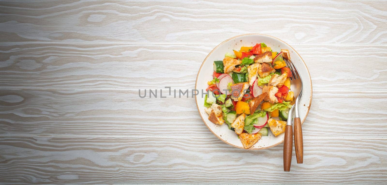 Traditional Levant dish Fattoush salad, Arab cuisine, with pita bread croutons, vegetables, herbs. Healthy Middle Eastern vegetarian salad, rustic wooden white background top view.