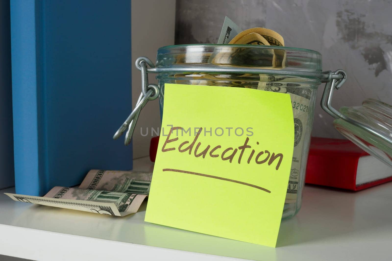 Glass jar containing savings for education and college sits on a shelf.
