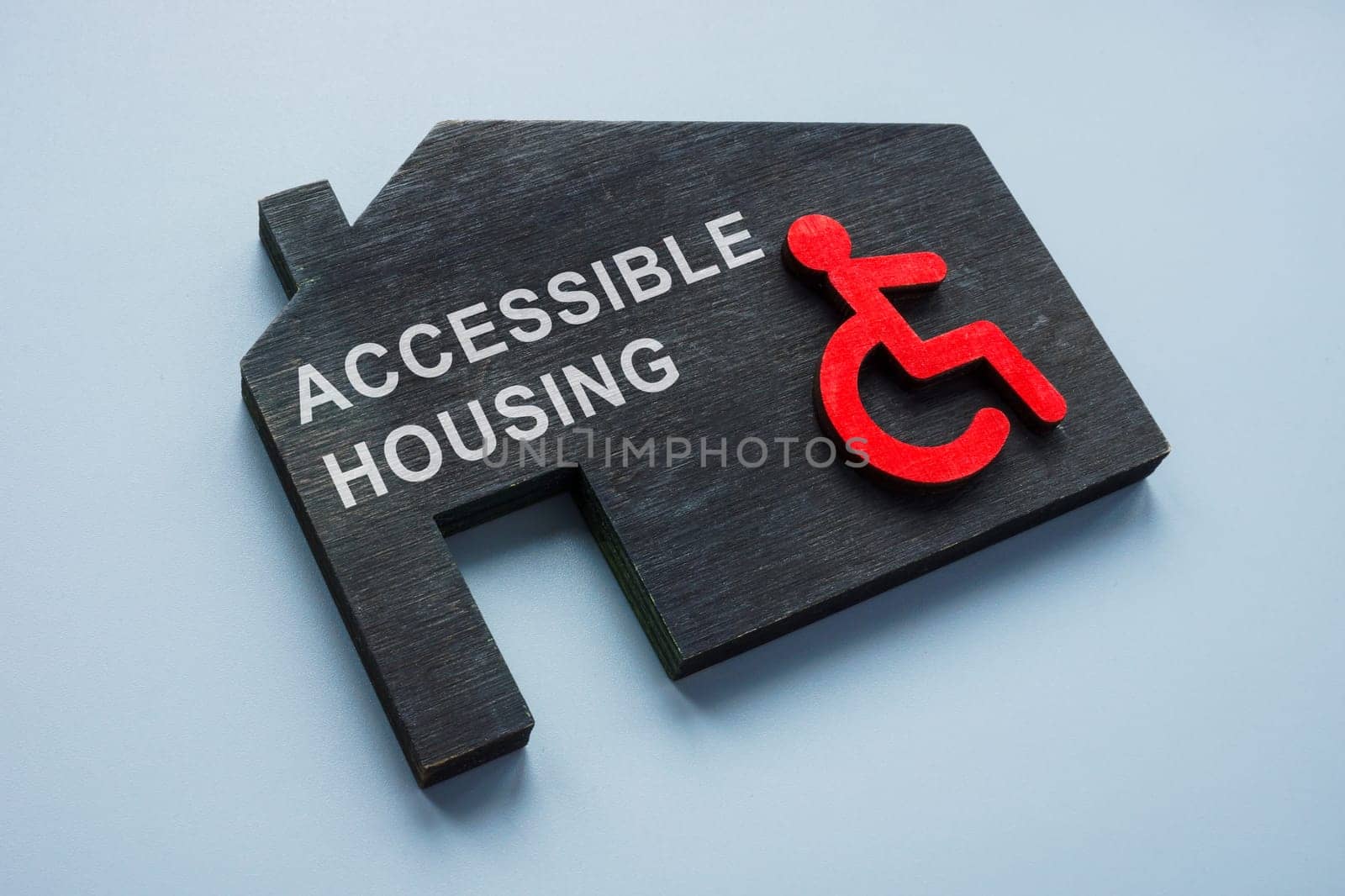 Accessible housing. Model of house and disabled person sign. by designer491