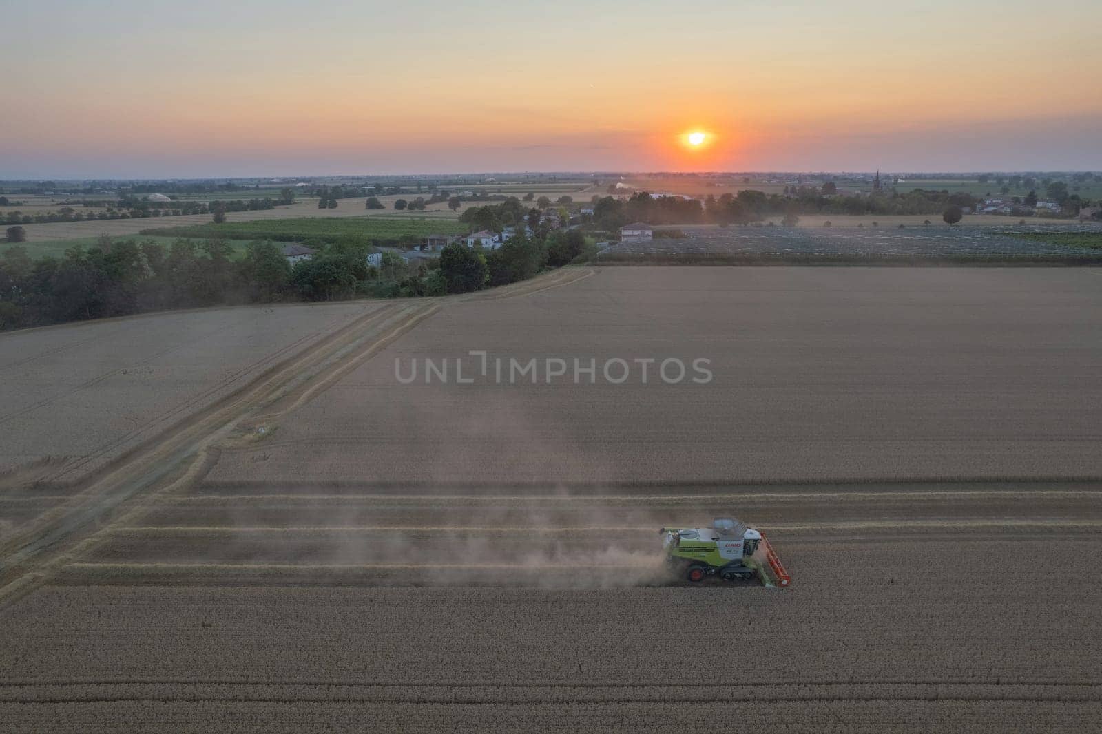 Soarza, Italy - June 23 2023 Claas 780 Lexion Combine Harvester threshing wheat in field at sunset