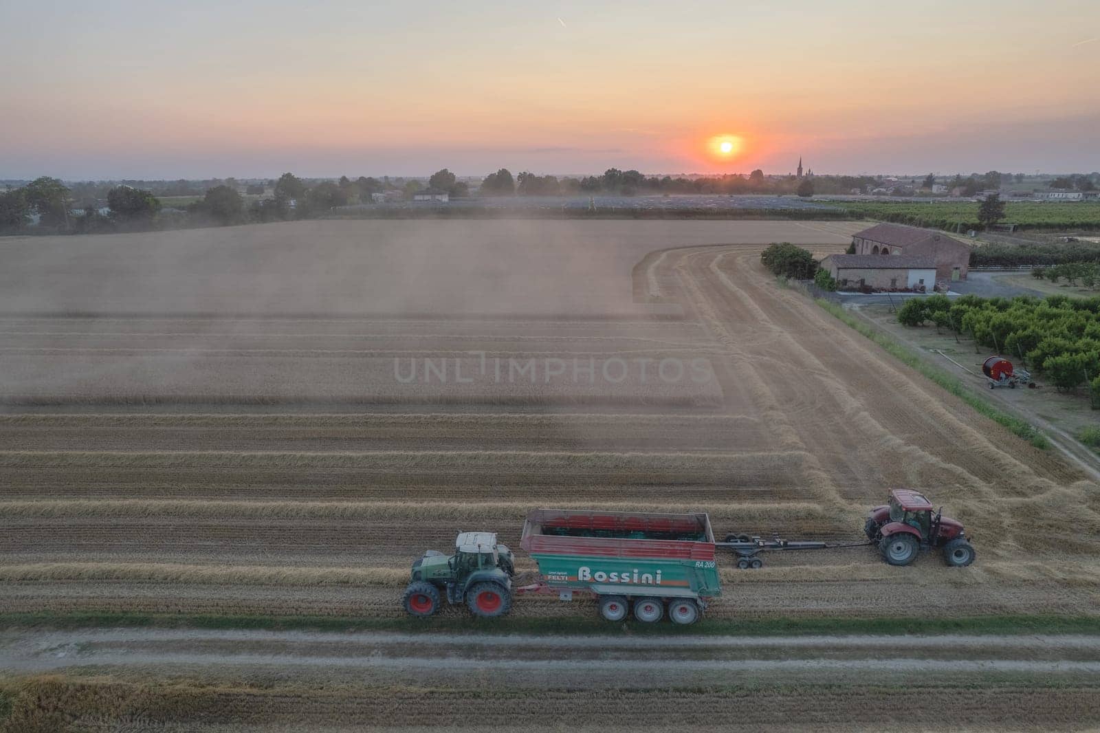 aerial view combine harvester threshing wheat grain in large field at early sunset in summer time by verbano