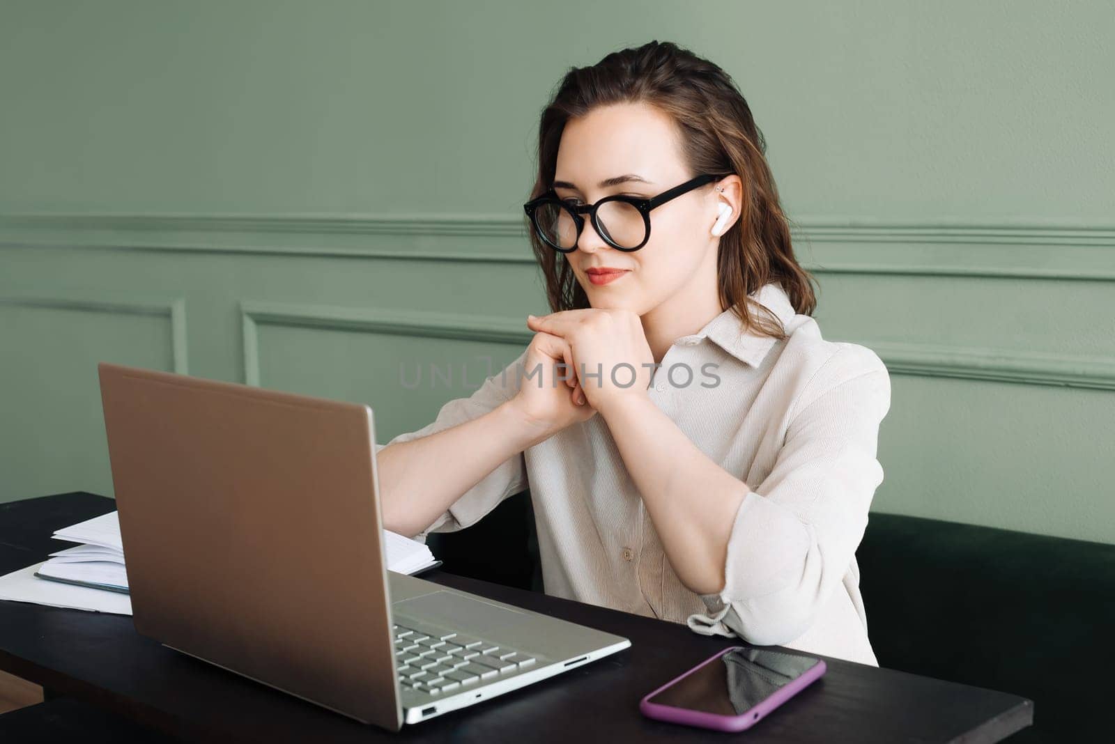 Connected and Smiling. Woman with Wireless Headphones Engages in Laptop Video Call with Joy. Digital Conversation. Woman in Goggles Smiles During Laptop Video Chat.