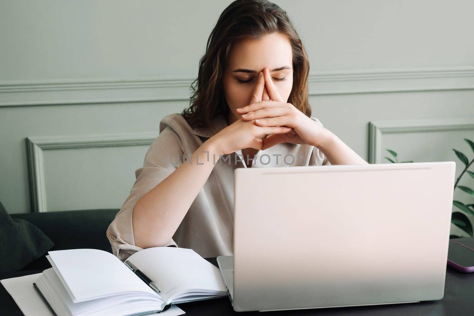 Stressed and Overworked: Unhappy Young Woman with Laptop Battling Fatigue, Pressure, Migraine, and Stress. Overworked and Stressed: Young Woman with Laptop Battling Fatigue, Pressure, Migraine, and Stress