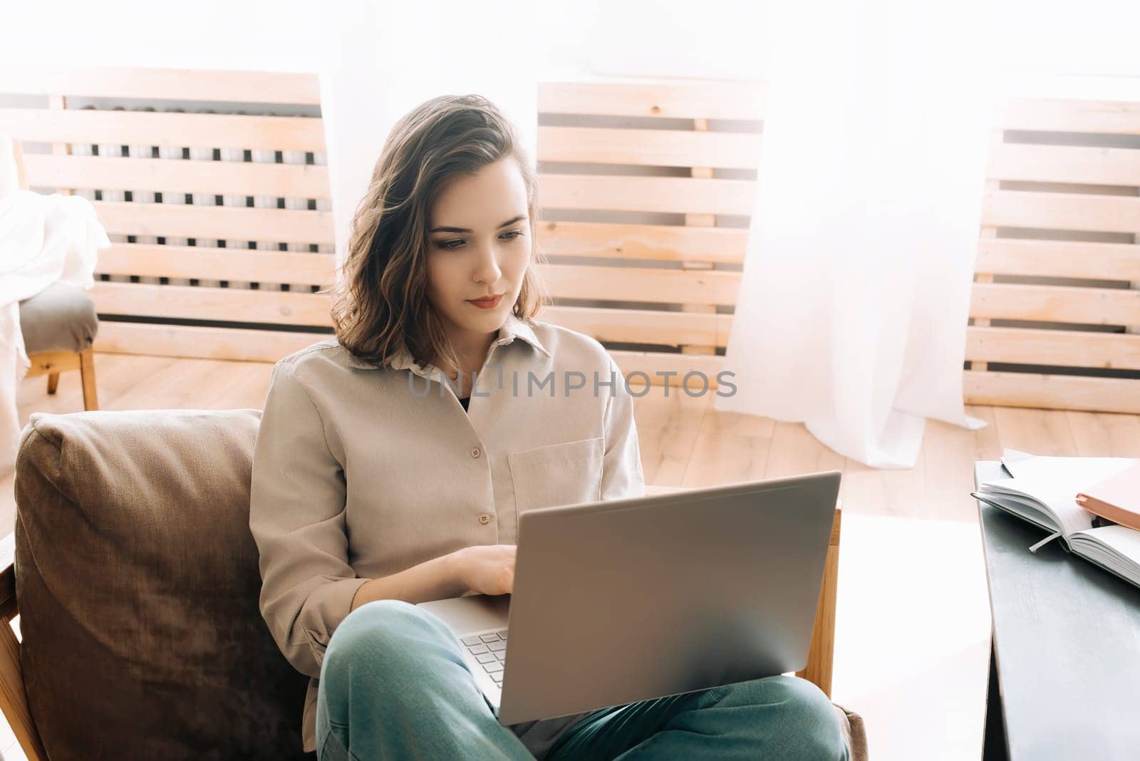 Modern Home Office. Woman Seriously Working on Laptop in Living Space. Efficient Remote Work. Woman Typing on Laptop in Living Room.