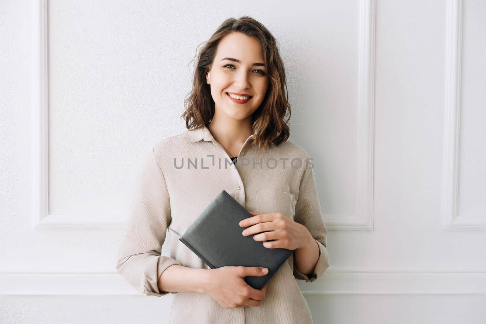 Smiling pretty young women in casual clothes with a notebook in hands, in the interior of the living room.