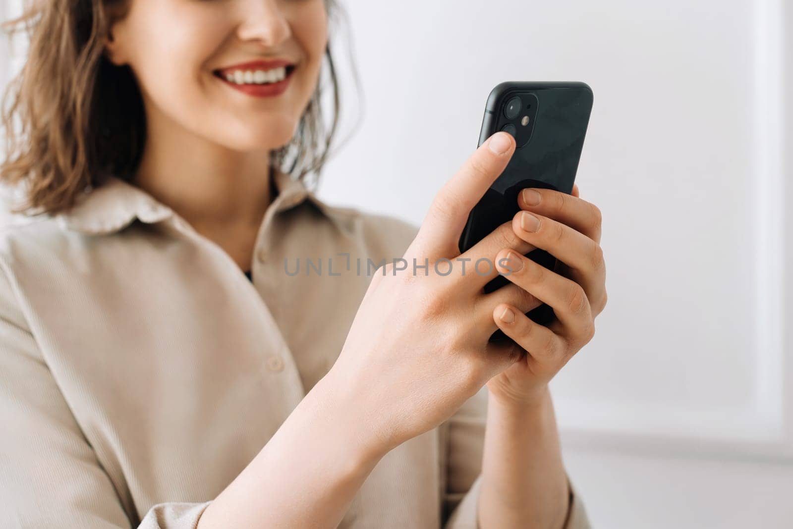 Smiling young woman typing on smartphone, chatting in social network, watch video. Digital Interaction Delight. Young Woman Smiles, Engaged in Smartphone Activities. Multitasking Maven.