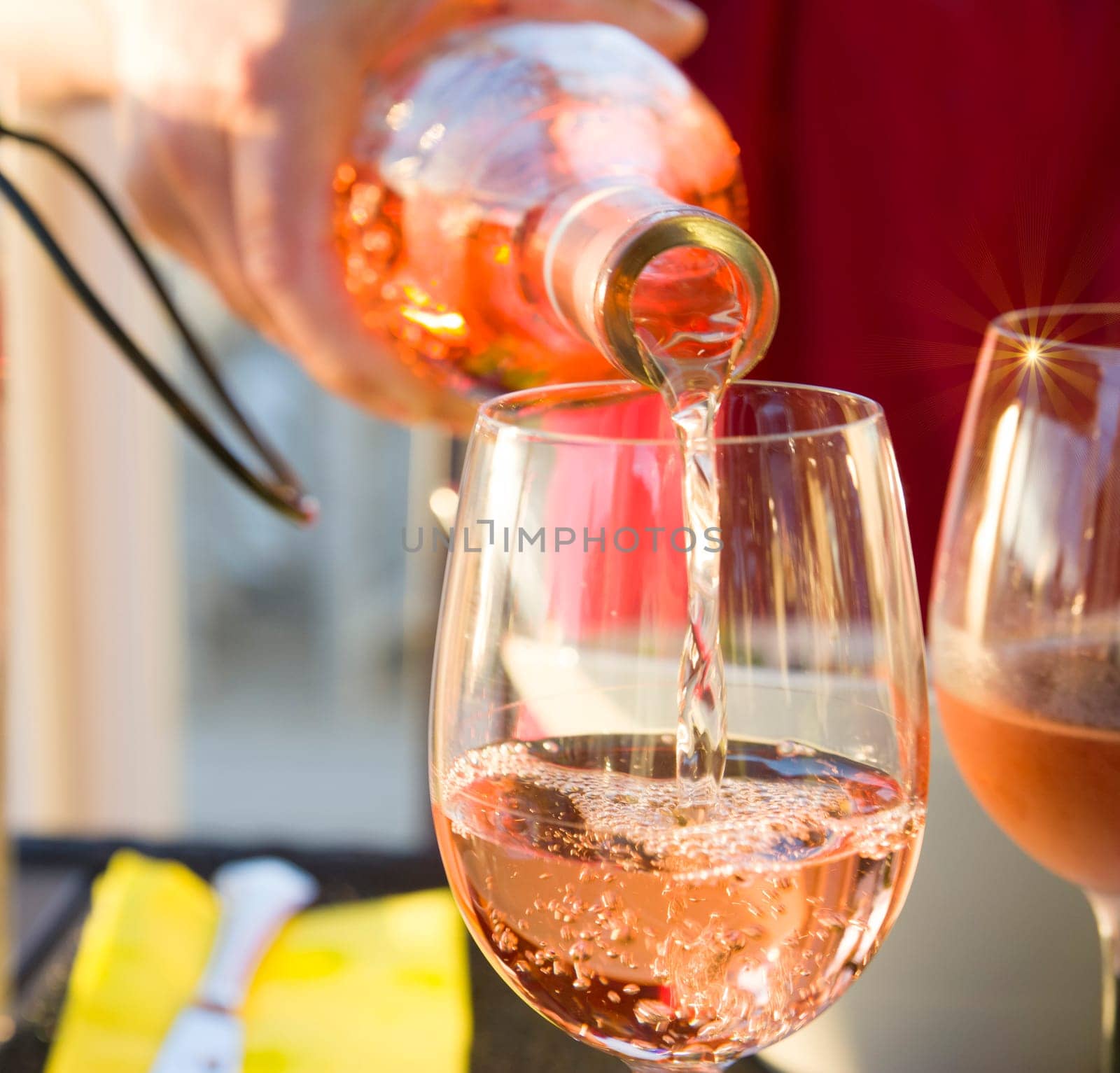 The waiter pours the pink french wine into the glass