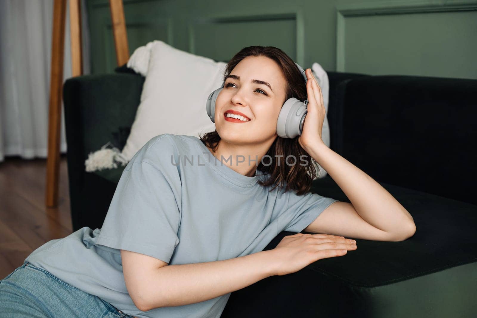 Thoughtful joyful young woman wearing wireless headphones listening to music while enjoying her free time. Musical Serenity. Young Woman Embracing Joyful Moments with Wireless Headphones.