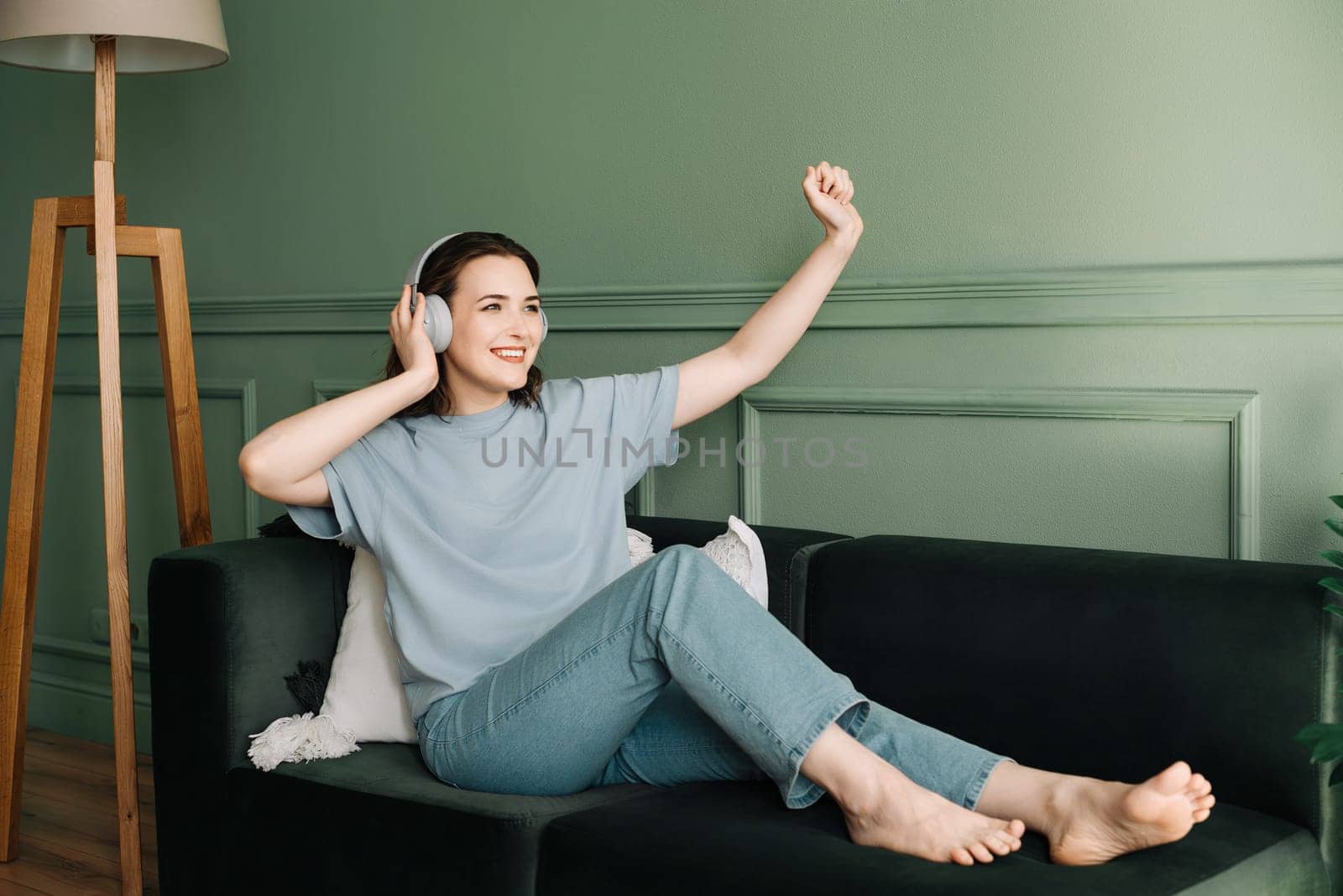 Happy young woman in wireless headphones listening to music while dancing. Rhythmic Euphoria. Joyful Woman Grooving to Music in Wireless Headphones. Musical Elation. Dance of Joy.