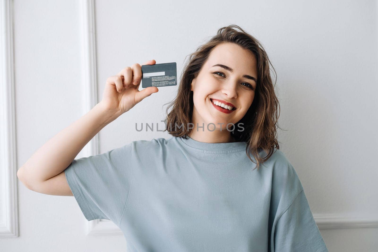 Smiling Middle-Aged Woman Displaying Credit Card in Studio Close-up. Cheerful Mature Woman Showing Credit Card in Studio, Close-up Shot. Joyful Middle-Aged Lady Displaying Credit Card with Smile.