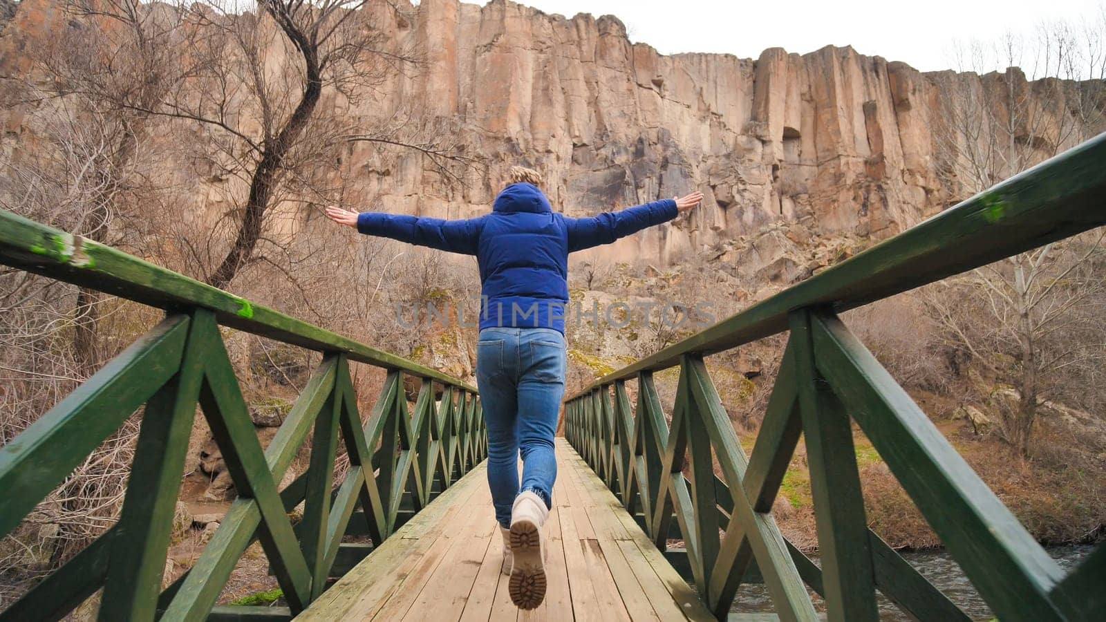 Happy tourist runs on a bridge over a river in the Ihlara Valley in Cappadocia, Turkey. by DovidPro