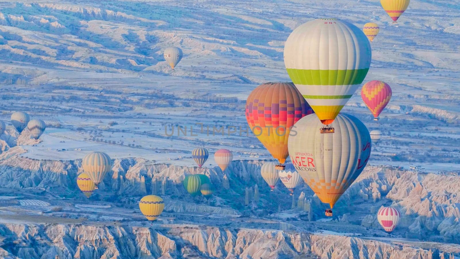 Cappadocia, Turkey - January 6, 2020: Color balloons in the sunrise sky. Cappadocia, Turkey. by DovidPro