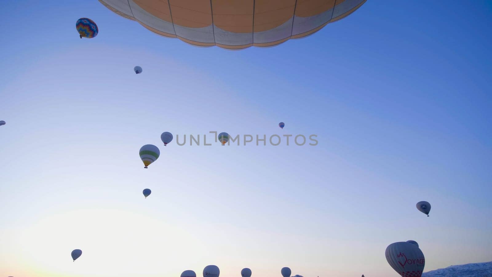 Cappadocia, Turkey - January 6, 2020: Color balloons in the sunrise sky. Cappadocia, Turkey. by DovidPro