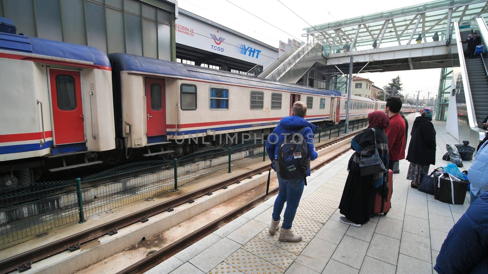 Ankara railway station with passengers and a passing train.