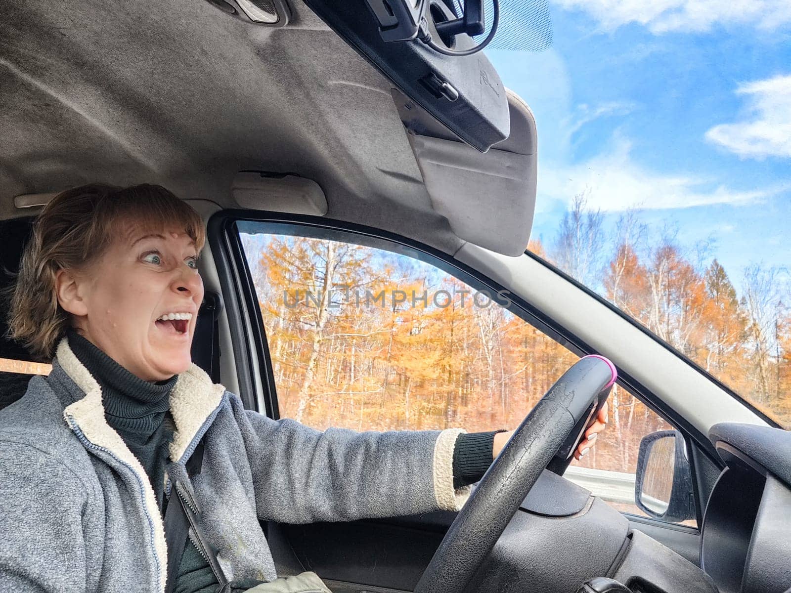Terrified female driver a second before the accident. Scared middle-aged adult woman holds the steering wheel of car. Frightened Lady girl who is owner or rent a car for travel