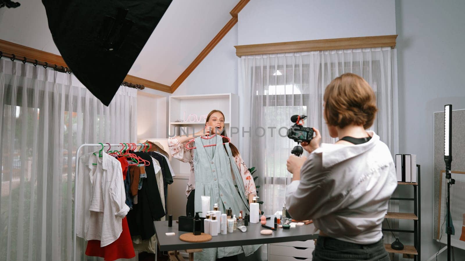 Two women influencer shoot live streaming vlog video review clothes prim social media or blog. Happy young girl with apparel studio lighting for marketing recording session broadcasting online.