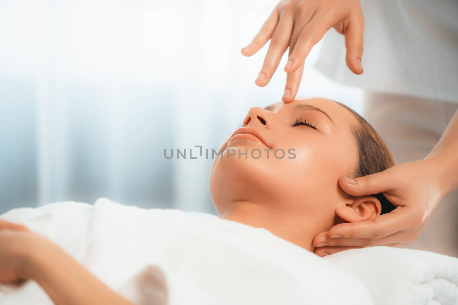 Caucasian woman enjoying relaxing anti-stress head massage and pampering facial beauty skin recreation leisure in dayspa modern light ambient at luxury resort or hotel spa salon. Quiescent