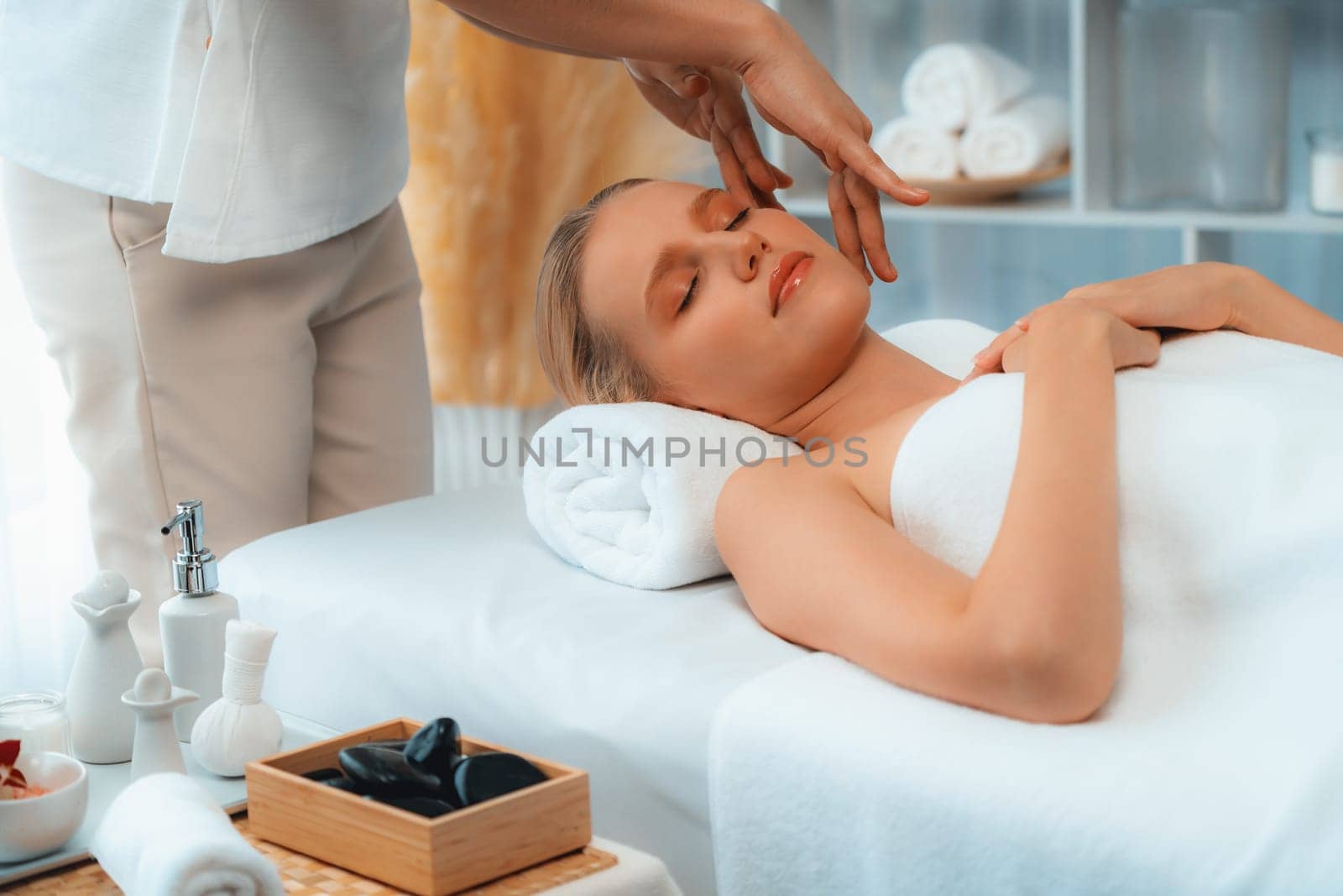 Caucasian woman enjoying relaxing anti-stress head massage and pampering facial beauty skin recreation leisure in dayspa modern light ambient at luxury resort or hotel spa salon. Quiescent