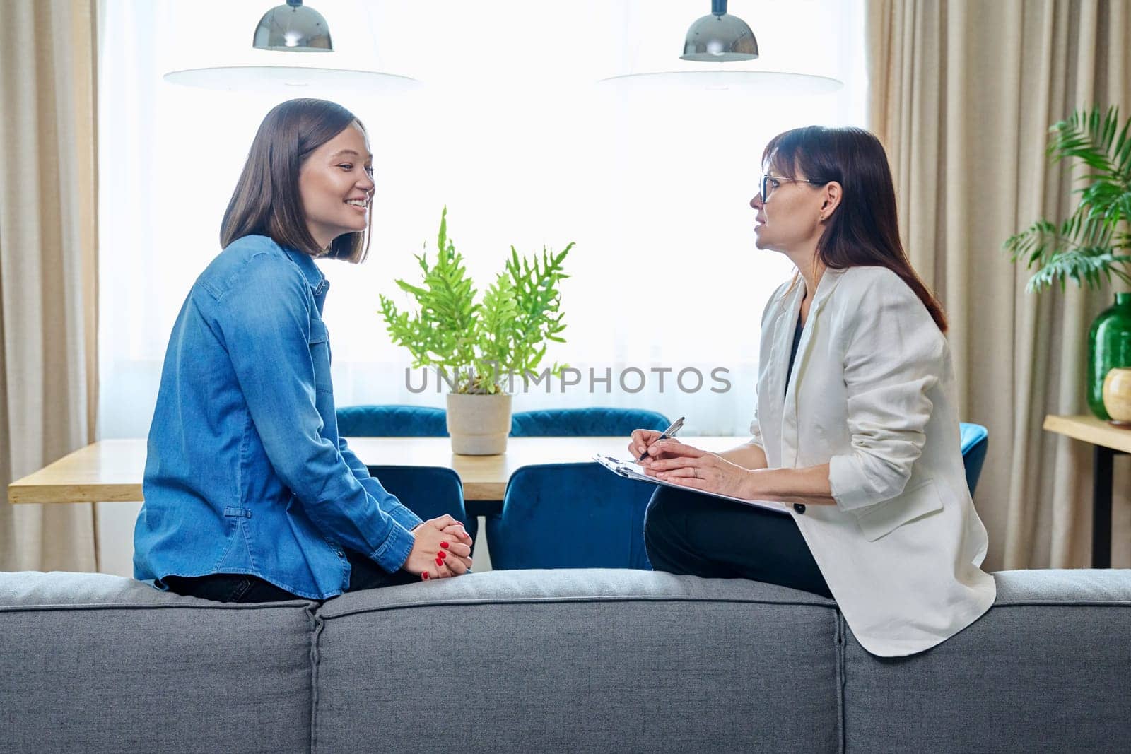 Happy joyful young woman patient talking to female psychologist counselor at therapy session. Positive treatment results, mental health of youth. Psychology psychotherapy support help rehabilitation