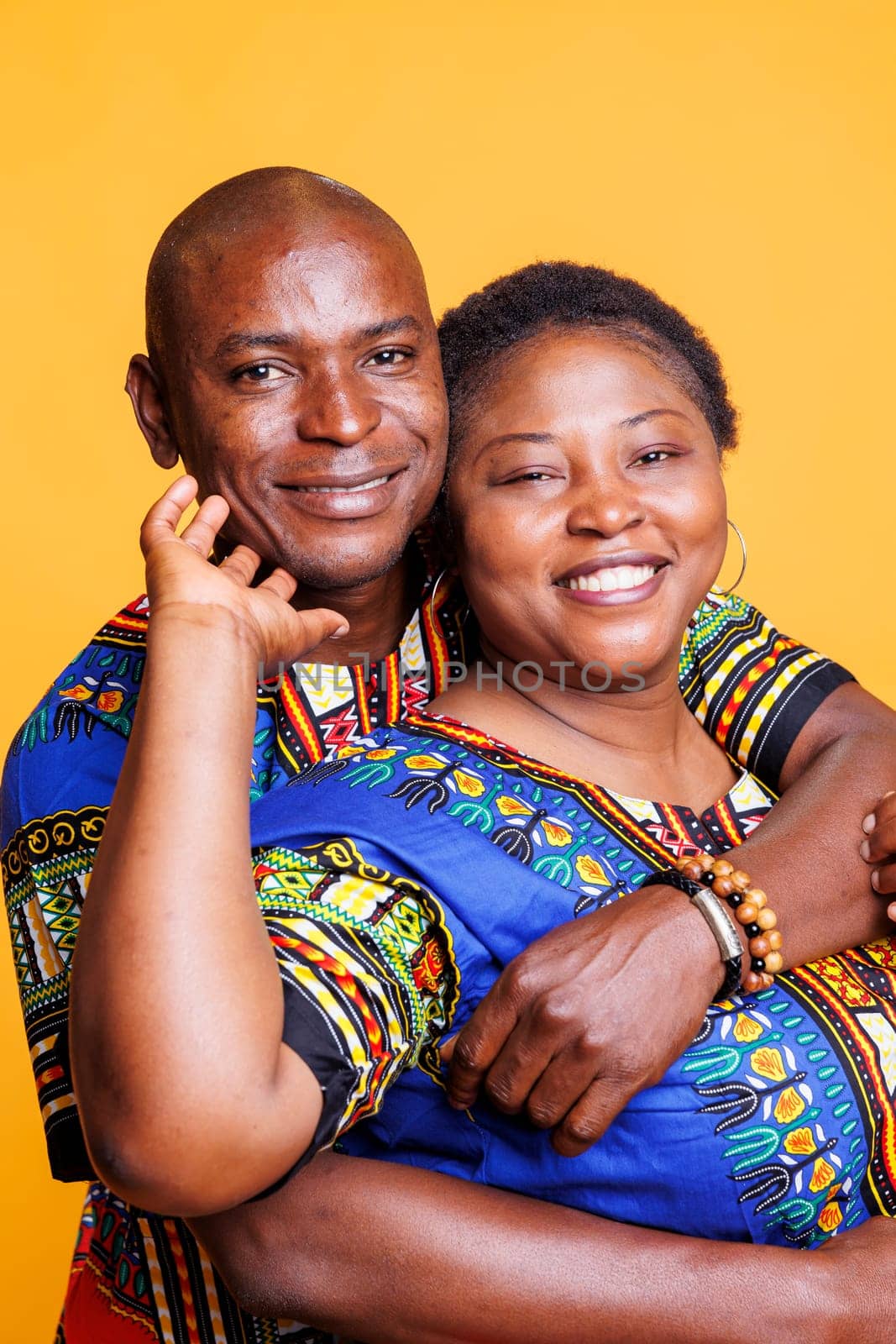 Smiling black couple in relationship embracing, showing love and happiness portrait. Joyful mature wife and husband romantic pair hugging and looking at camera with cheerful expression