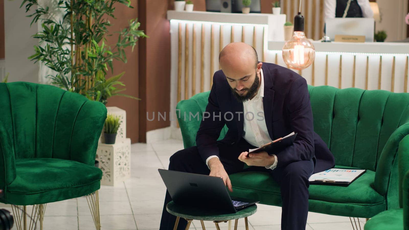 Shareholder using laptop at hotel, searching for solutions to increase company budget at international board meeting. White collar worker waiting to start conference in lounge area.