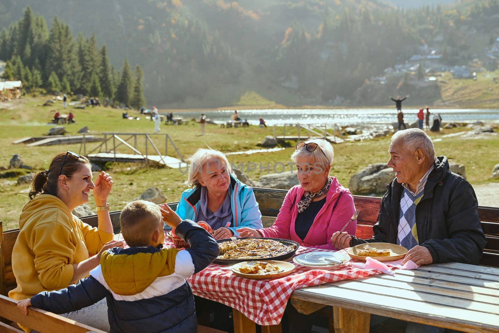 A family on a mountain vacation indulges in the pleasures of a healthy life, savoring traditional pie while surrounded by the breathtaking beauty of nature, fostering family bonds and embracing the vitality of their mountain retreat.