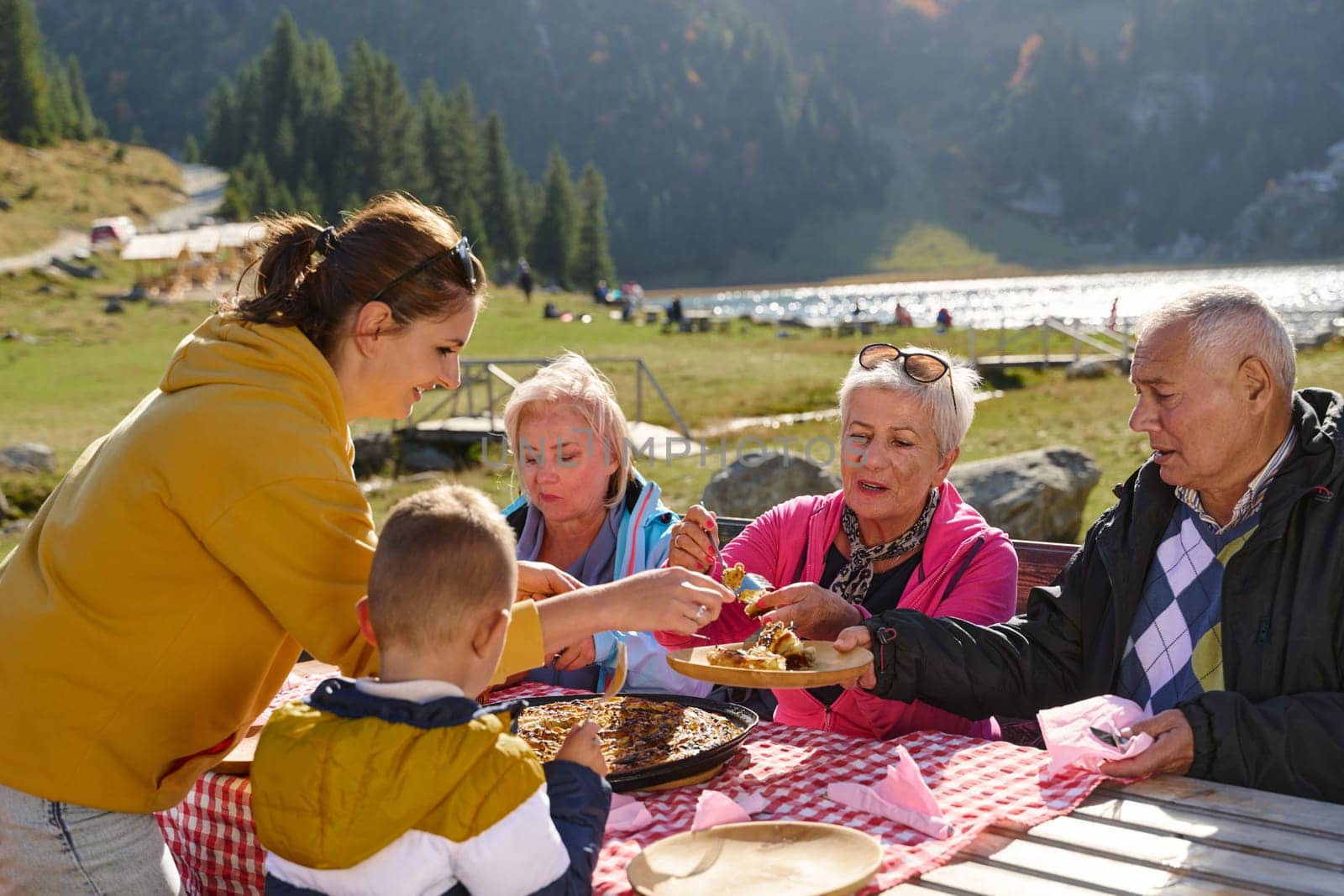 A family on a mountain vacation indulges in the pleasures of a healthy life, savoring traditional pie while surrounded by the breathtaking beauty of nature, fostering family bonds and embracing the vitality of their mountain retreat by dotshock