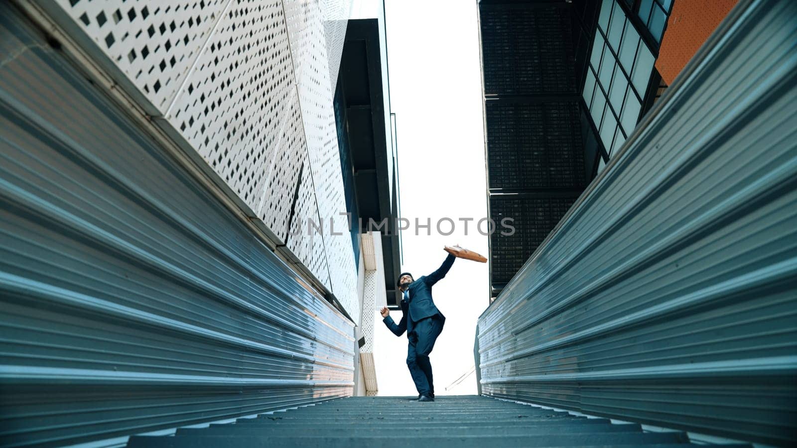 Low angle view of young smiling business man dance between building. Exultant. by biancoblue